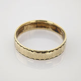 Goldring mit 18k Punze und welligem Rand auf reflektierendem Untergrund.