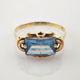 Goldring mit blauem Edelstein auf weißem Hintergrund