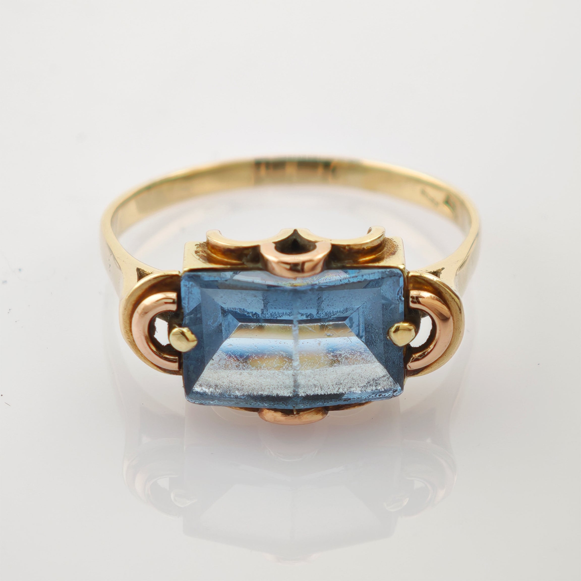 Goldring mit blauem Edelstein auf weißem Hintergrund