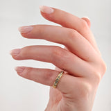 Feiner Goldring mit mehreren funkelnden Diamanten am Mittelfinger einer gepflegten Hand mit glänzend lackierten Nägeln.