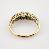 Goldring mit filigraner Offenarbeit und drei grünen Steinen auf weißem Hintergrund