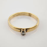 Goldring mit schmalem Band und kleinem rundem klaren Edelstein in Vier-Krappen-Fassung.