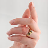 Hand mit gepflegten, hellrosa Nägeln trägt einen goldenen Ring mit kleinem Diamanten am Ringfinger