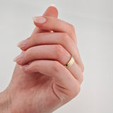 Hand mit rosa lackierten Fingernägeln und goldfarbenem Ring am Ringfinger