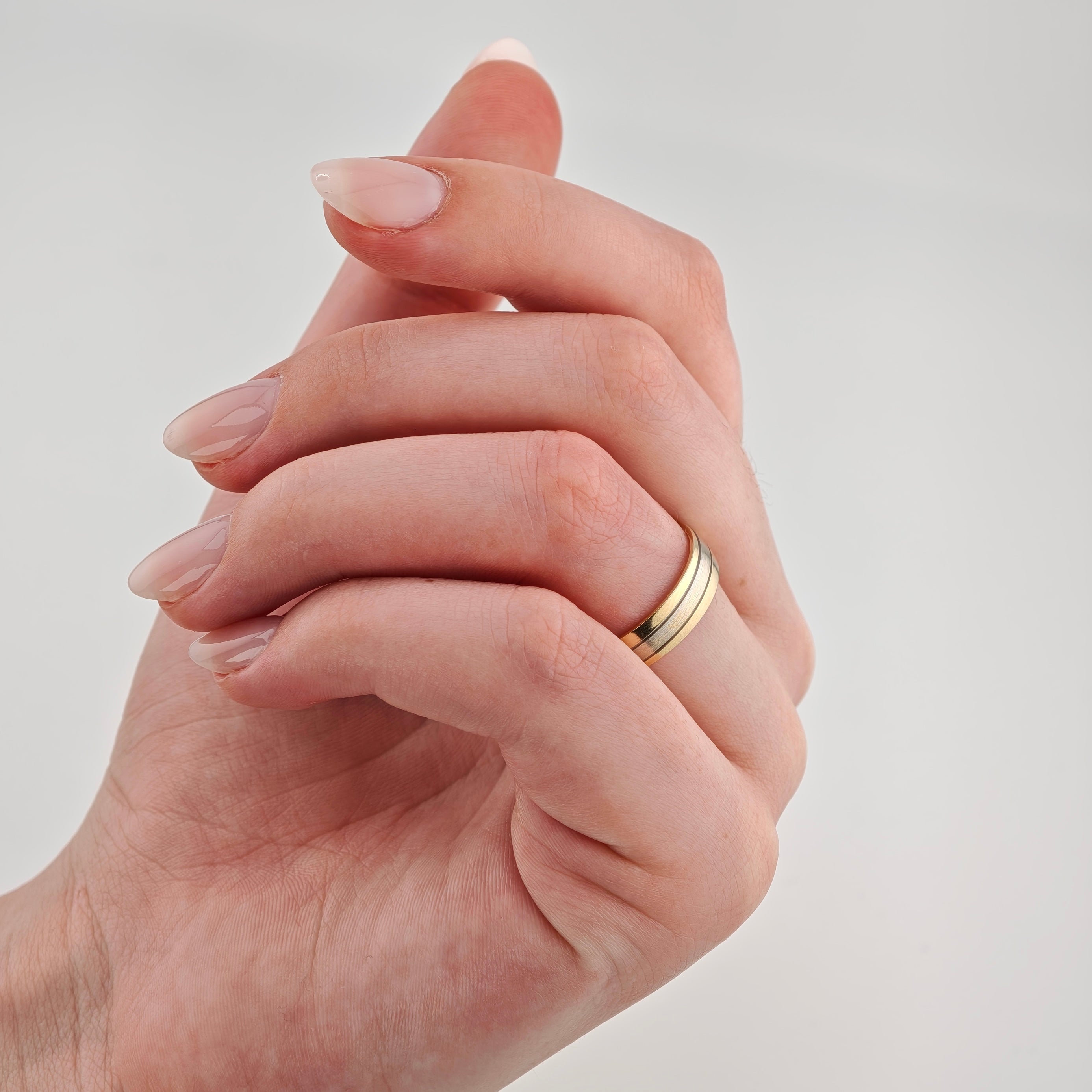 Hand mit rosa lackierten Fingernägeln und goldfarbenem Ring am Ringfinger