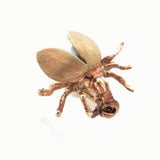 Kleine Metallskulptur eines Käfers mit geöffneten Flügeln und blauem Unterteil auf weißem Hintergrund.