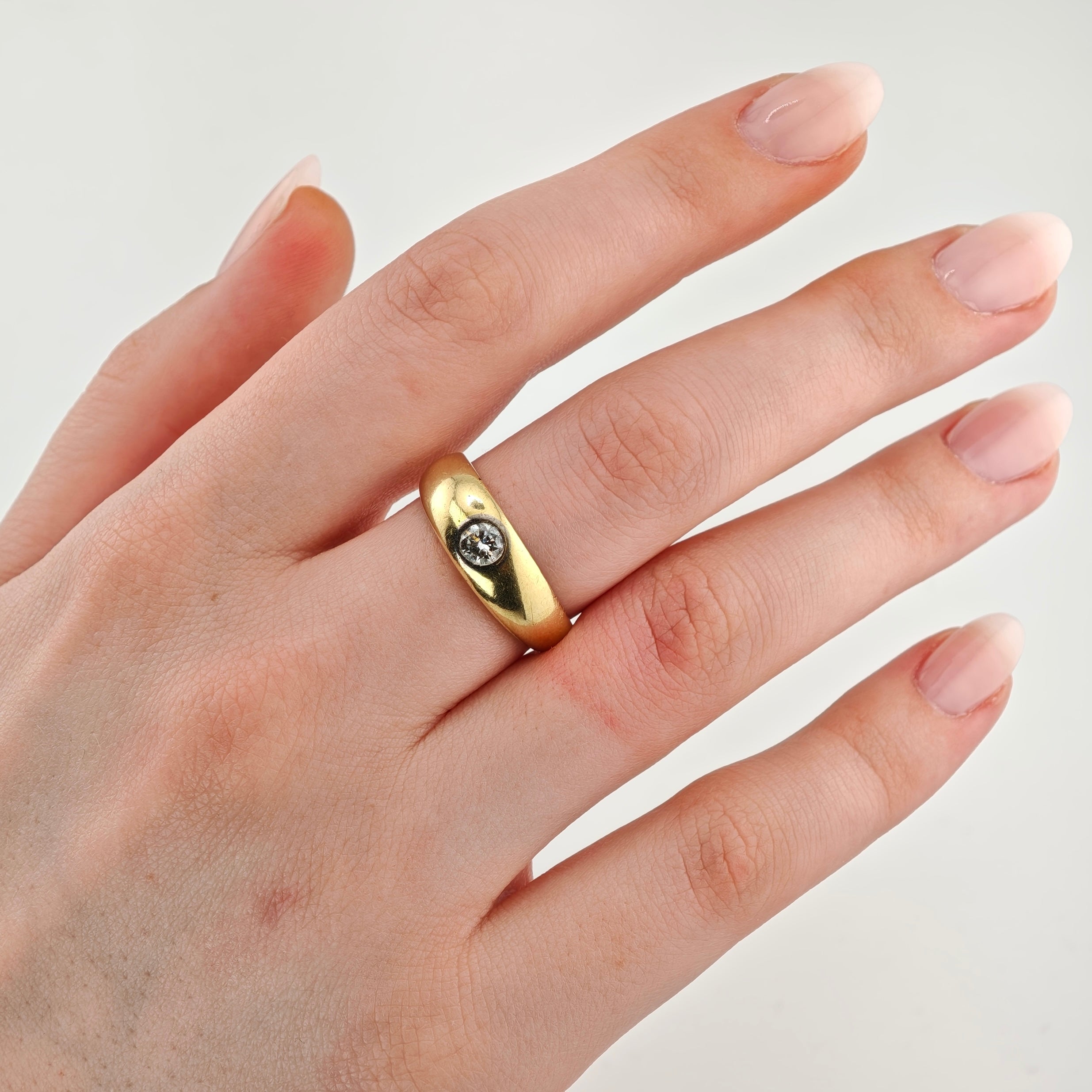 Linke Hand mit gepflegten Nägeln in rosafarbenem Verlauf und Goldring mit klarem Stein am Ringfinger.