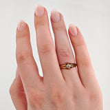 Linke Hand mit hellrosa und beige lackierten Nägeln, Goldring mit klarem Edelstein am Ringfinger.