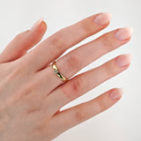 Linke Hand mit natürlicher ovaler Maniküre trägt schlichten Goldring mit kleinem Diamant auf Ringfinger.