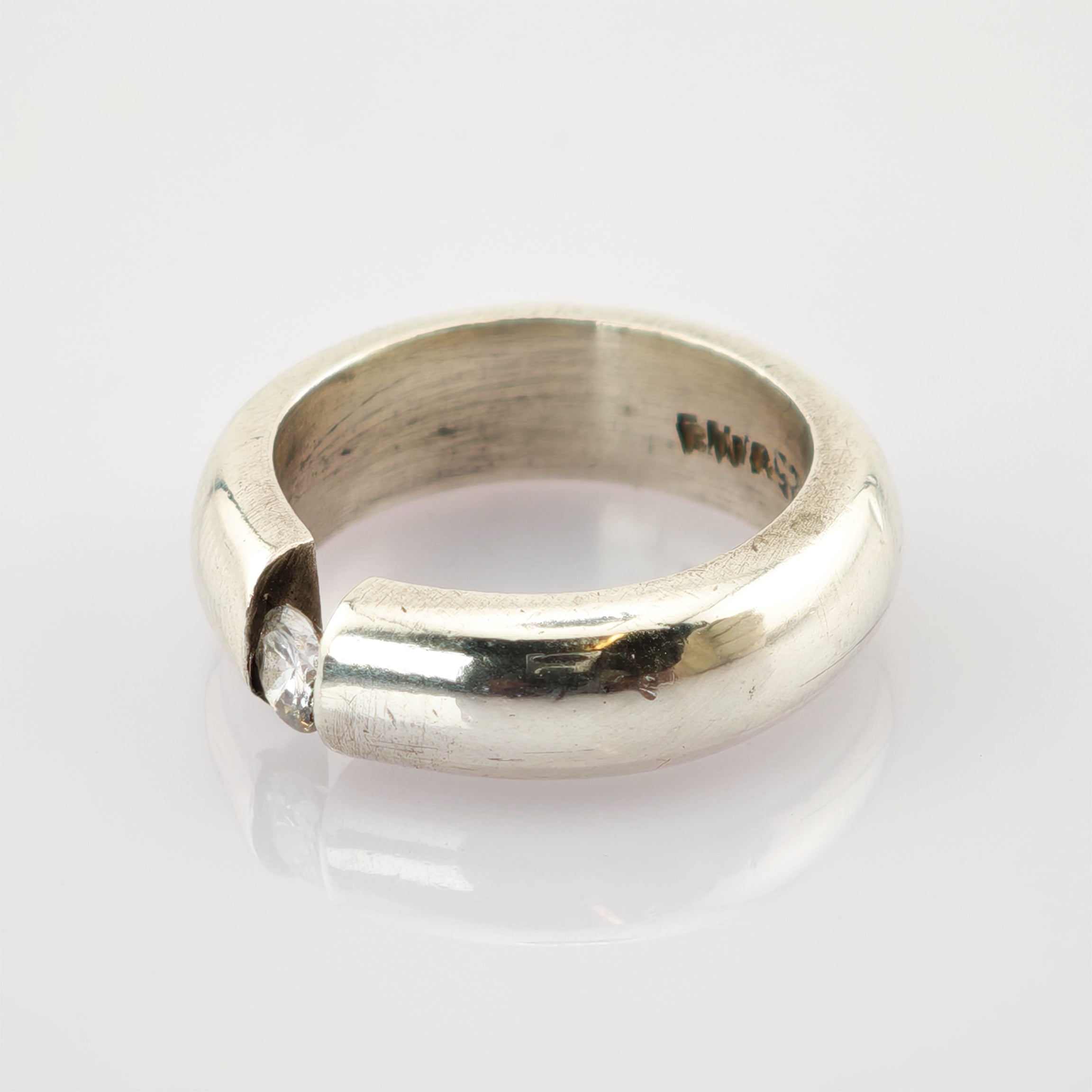 Massiver Silberring mit polierter Oberfläche und geteilter Öffnung, klarem diamantähnlichem Stein und F. Mirás Gravur innen.