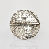 Metallisches Objekt mit strukturierter, rissiger Oberfläche, unterteilt in Segmente, mit glänzendem Silberfinish