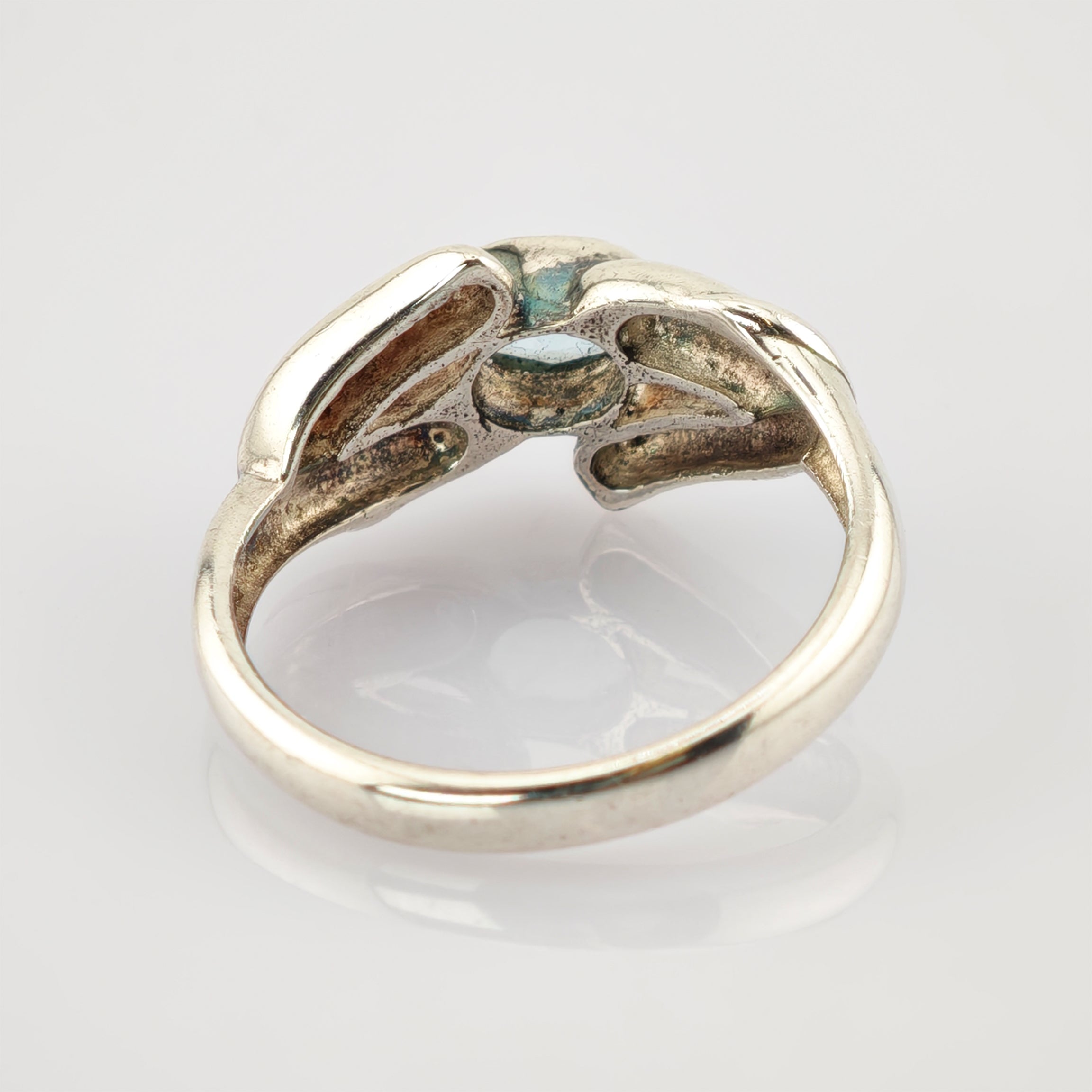 Metallring mit zwei Händen, die einen blauen Edelstein halten. Eleganter Vintage-Schmuck.