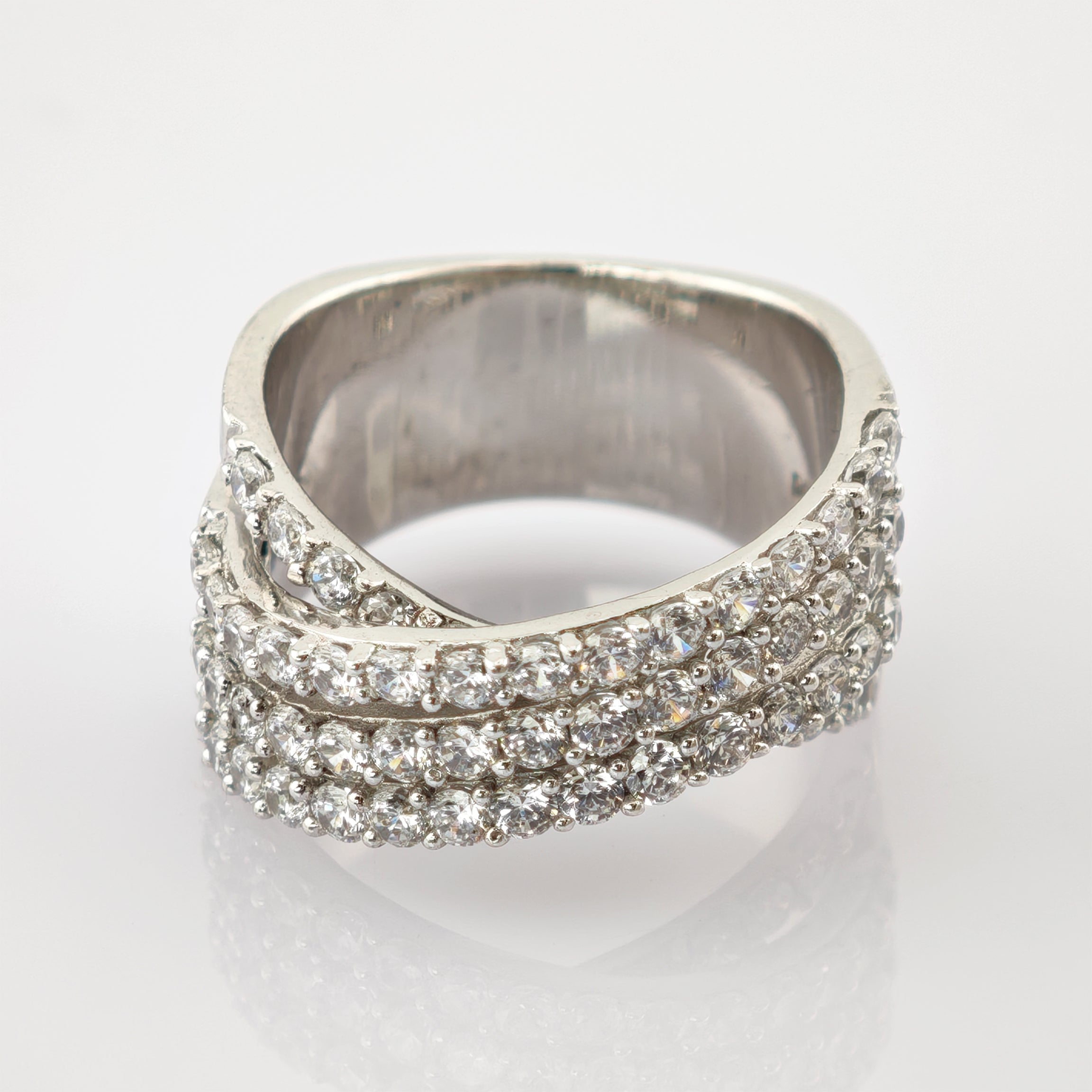 Moderner Silberring mit zwei Reihen funkelnder runder klarer Steine im Wellenmuster auf weißem Hintergrund