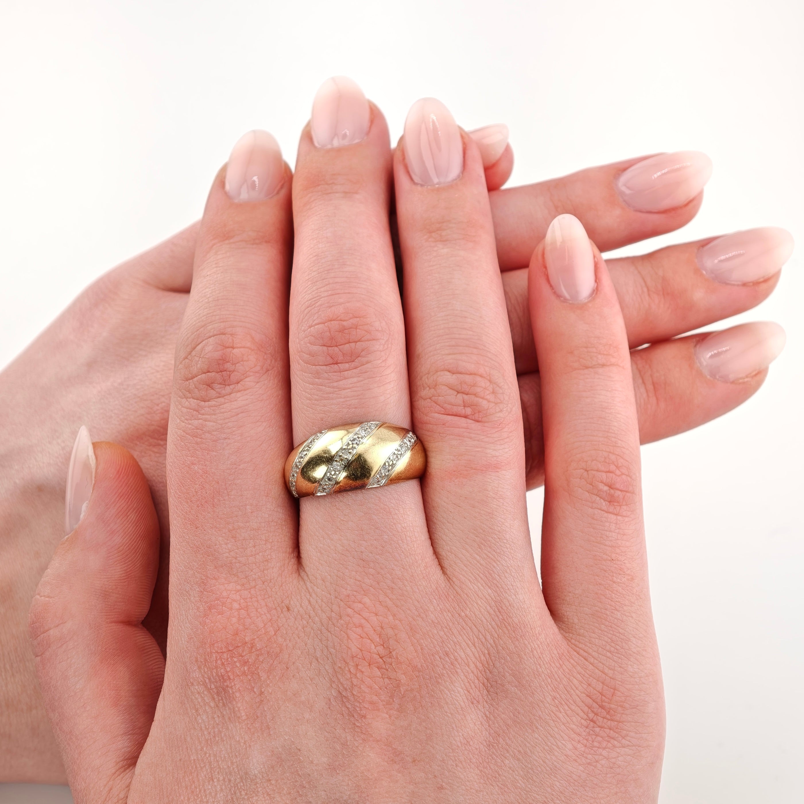 Nahaufnahme zweier Hände mit gepflegten Nägeln, ein goldener Ring mit kleinen Diamanten.