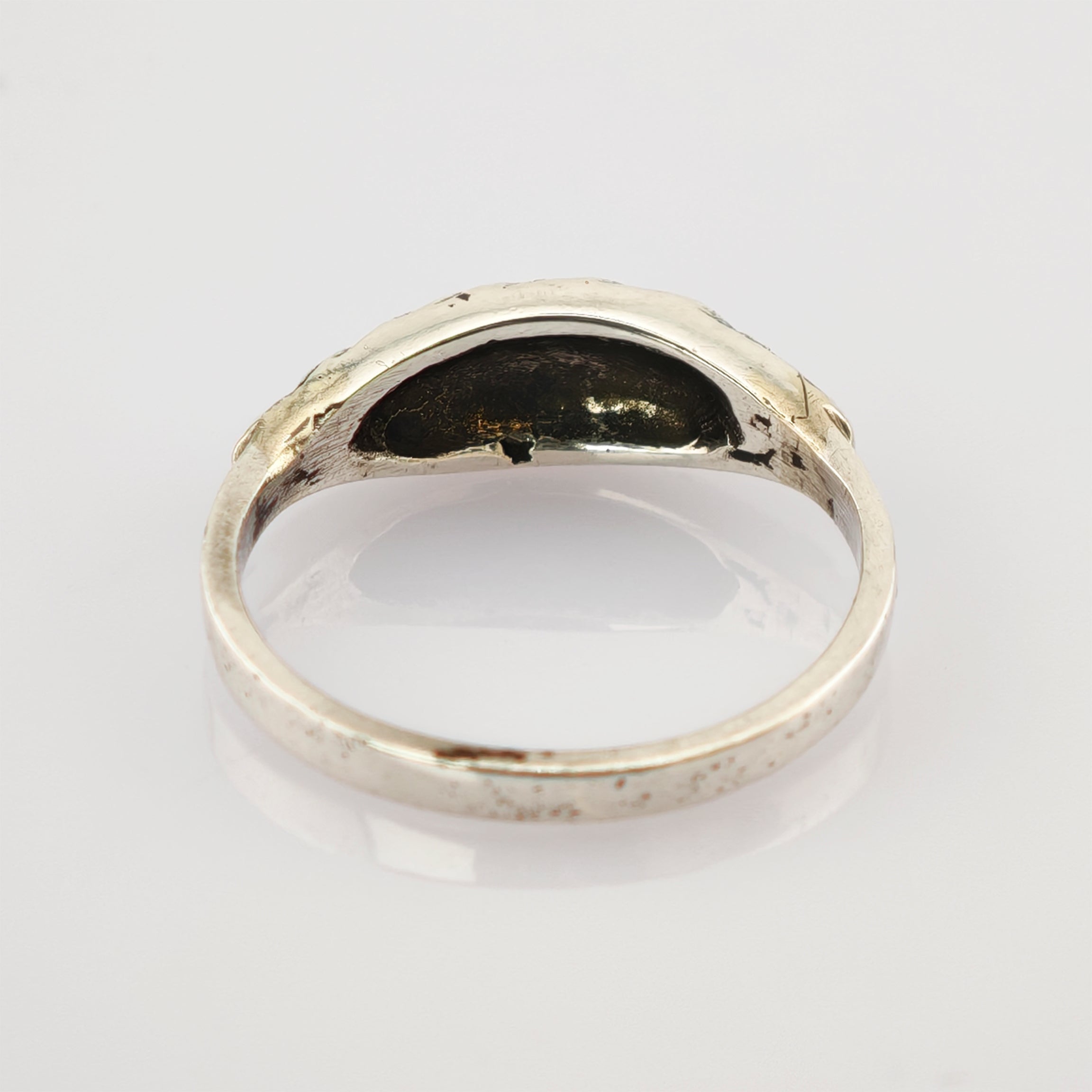 Nahaufnahme eines silbernen Rings mit glatter, leicht gebogener Oberfläche und dunkler Patina innen.
