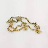 Nahaufnahme einer verhedderten goldenen Kette mit ovalen Gliedern auf weißem Hintergrund.