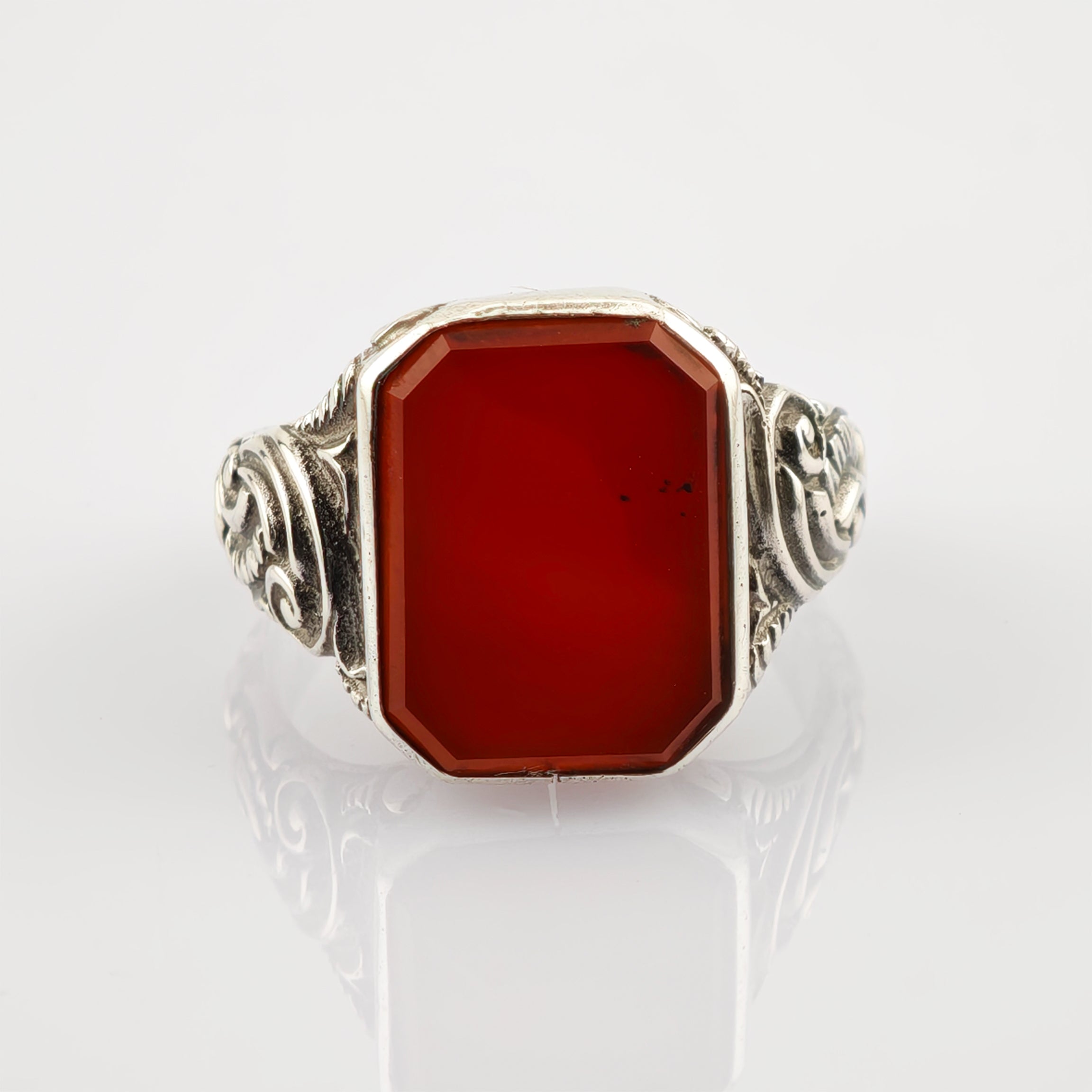 Ornamentierter silberner Ring mit rechteckigem rotem Edelstein und Gravuren