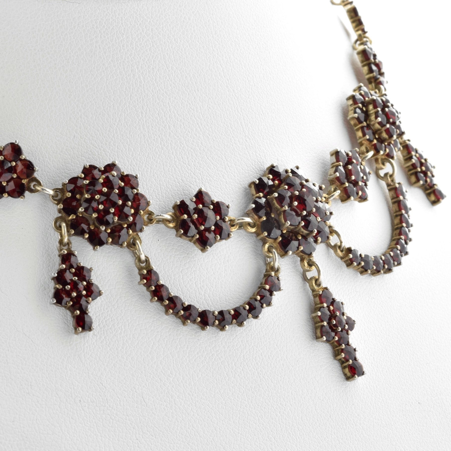 Ornate Halskette aus goldfarbenem Metall mit tiefroten Edelsteinen in floralen und geometrischen Mustern.