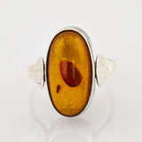 Ovaler Bernstein in Silberring mit dreieckigen Seitenakzenten und natürlichem Orange-Braun