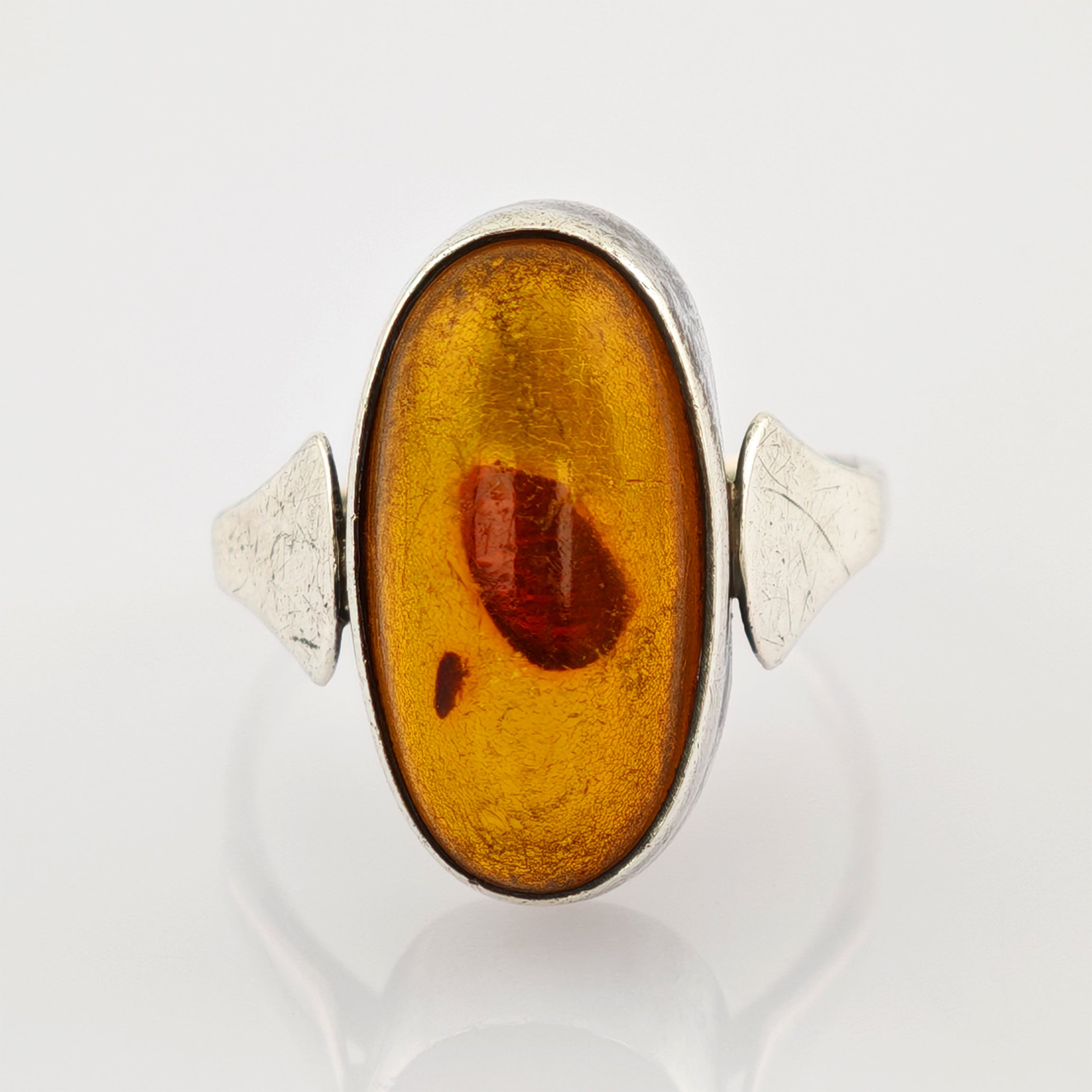 Ovaler Bernstein in Silberring mit dreieckigen Seitenakzenten und natürlichem Orange-Braun