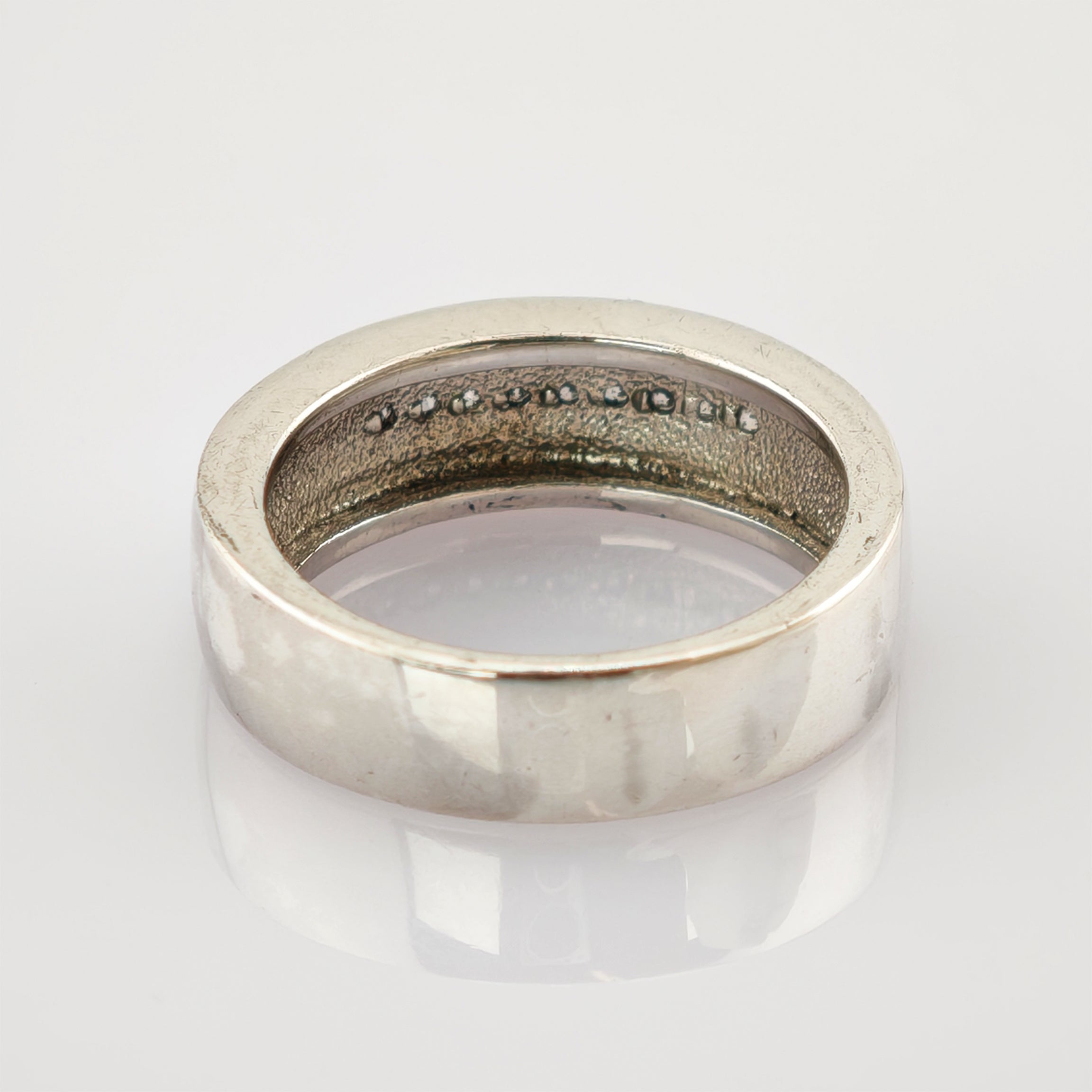 Polierter silberner Ring mit 925 Sterling Silber Stempel auf reflektierender weißer Oberfläche