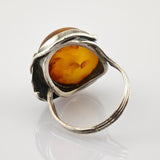 Retro-Ring mit großem, rundem Bernstein in warmen Gelb-Orange-Tönen auf silberner Band mit Gravuren.