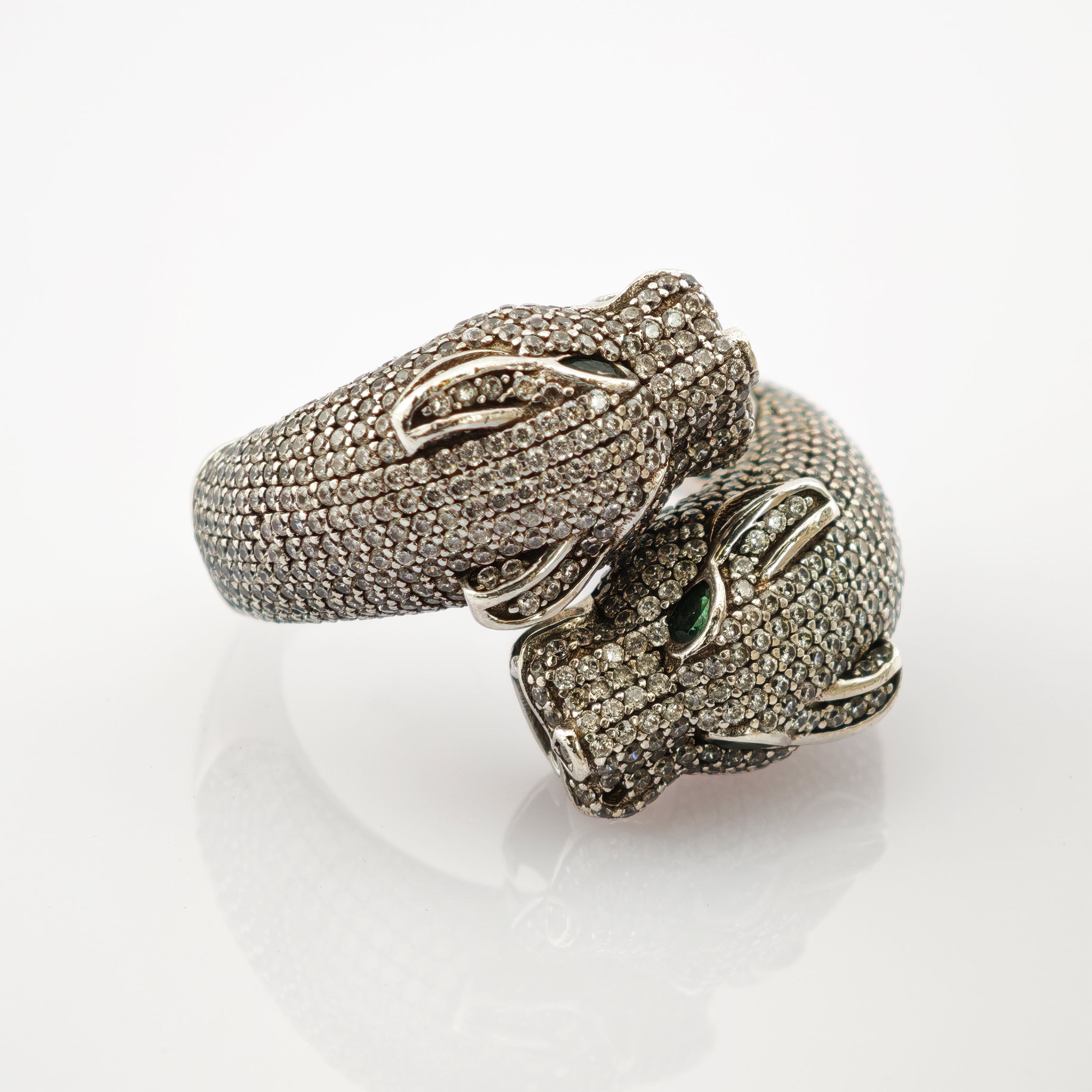 Ring mit zwei Drachenköpfen, funkelnden Steinen und grünen Edelsteinaugen, silberne Akzente
