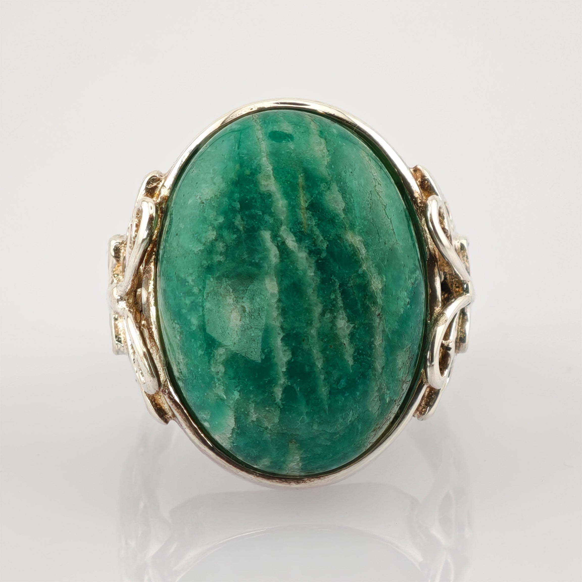 Nahaufnahme eines Rings mit großem ovalem grünen Stein und kunstvollem silbernem Band mit verzierter Struktur