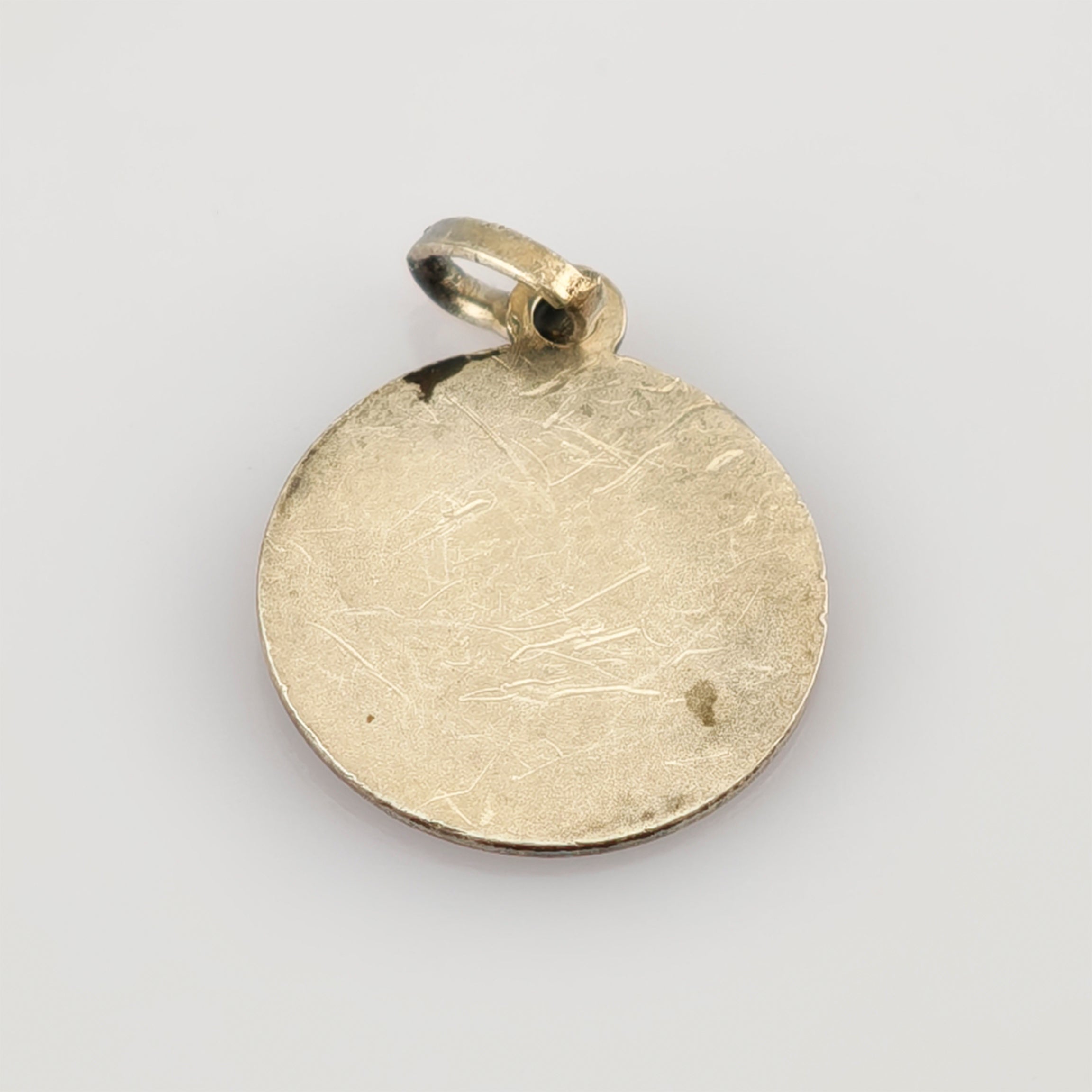 Rundes, leicht verkratztes Metallanhängsel mit Befestigungsschlaufe im minimalistischen Vintage-Stil.