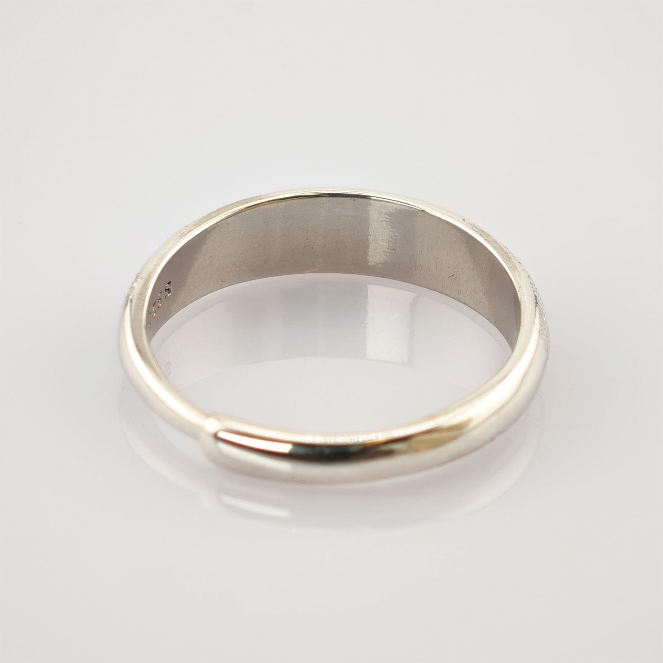 Schlichter Silberring mit glatter, polierter Oberfläche und 925-Punzierung auf weißem Hintergrund.