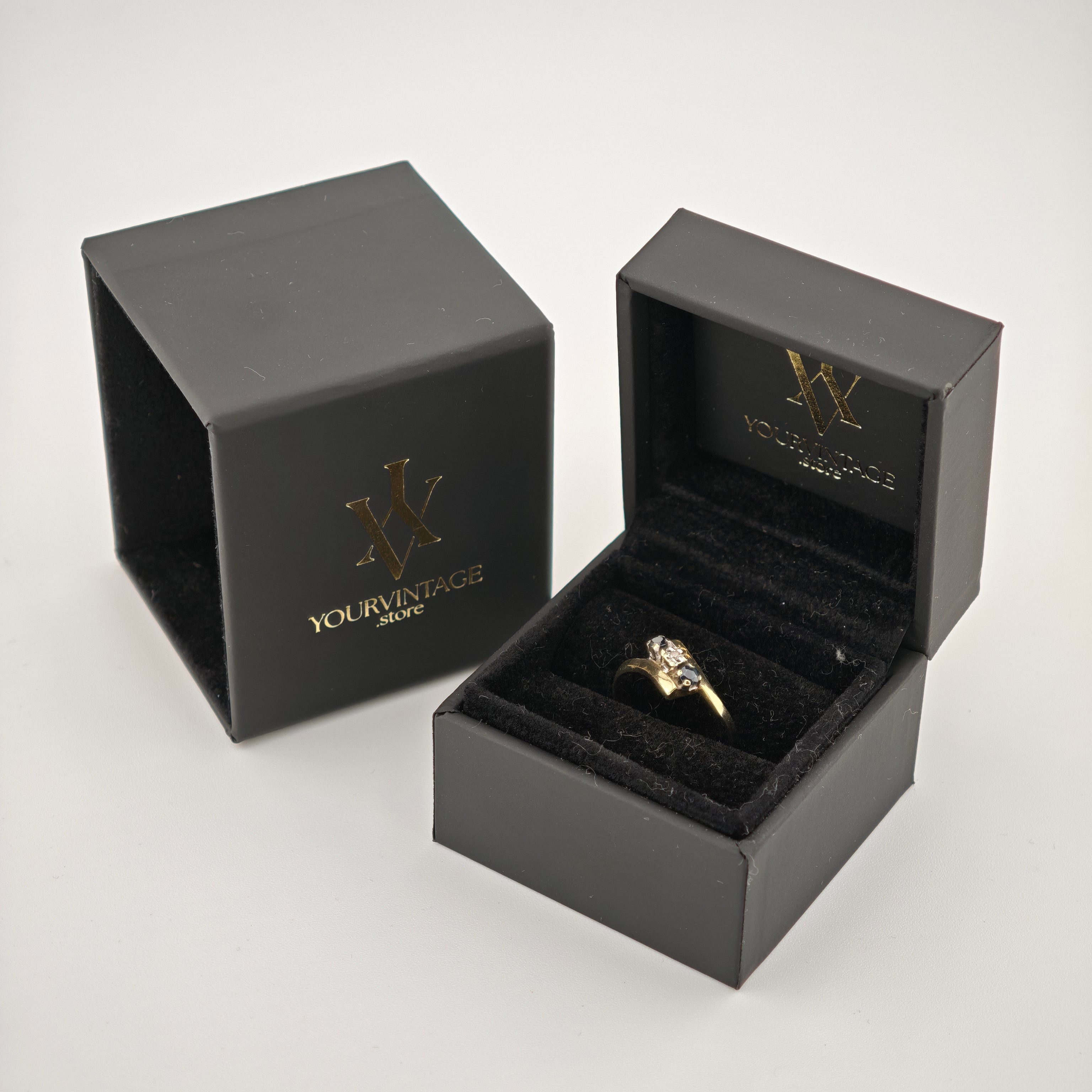 Schwarze Schmuckschachteln mit goldenem YOURVINTAGE.store-Schriftzug, eine offen mit goldfarbenem Ring auf schwarzem Samt.