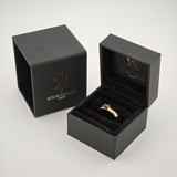 Schwarze Samtschmuckschachteln mit Goldlogo und Goldring mit dunkelblauem Stein auf weißem Hintergrund.