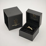 Offene und geschlossene schwarze Schmuckboxen mit goldenem W-Logo, offen mit goldenem Ring und kleinem Diamanten.