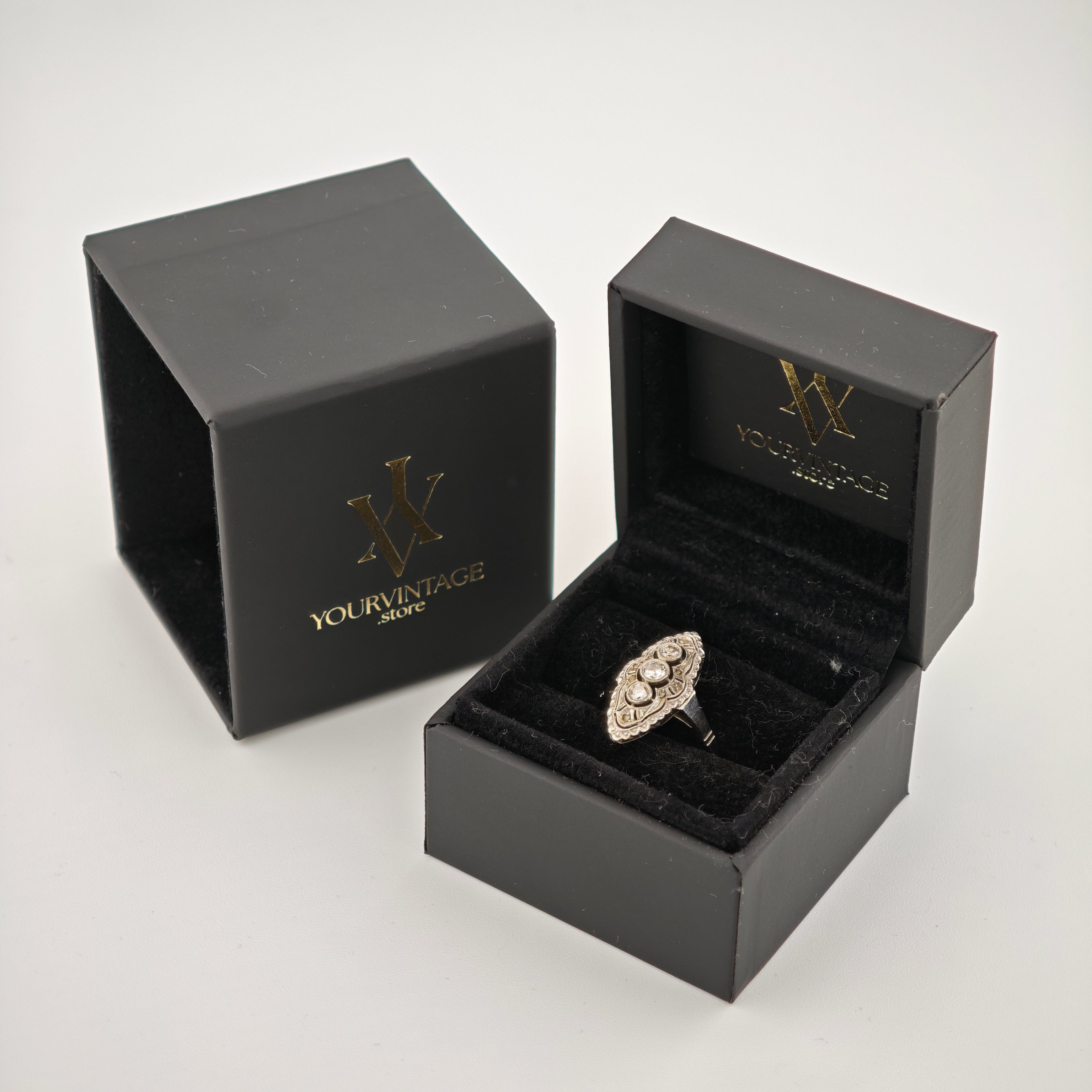 Schwarze Schmuckschatulle mit goldenem YOURVINTAGE.store Logo, offene Box zeigt silbernen Ring mit drei Steinen