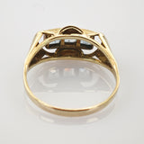Seitliche Ansicht eines Goldrings mit einem blauen Edelstein in dreieckiger Fassung auf weißem Seitliche Ansicht eines Goldrings mit sichtbarem Ringband und Edelsteinfassung.