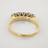 Seitliche Ansicht eines Goldrings mit fünf Diamanten, gehalten von silbernen Krappen, auf weißem Untergrund.