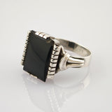Silberner Ring mit großer rechteckiger schwarzer Steinfassung und geteiltem Ringband auf weißem Hintergrund
