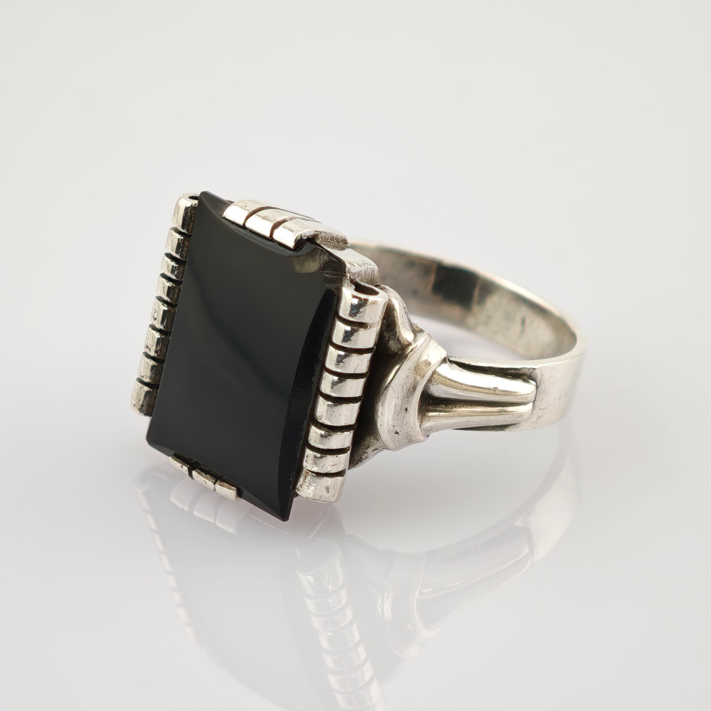Silberner Ring mit großer rechteckiger schwarzer Steinfassung und geteiltem Ringband auf weißem Hintergrund