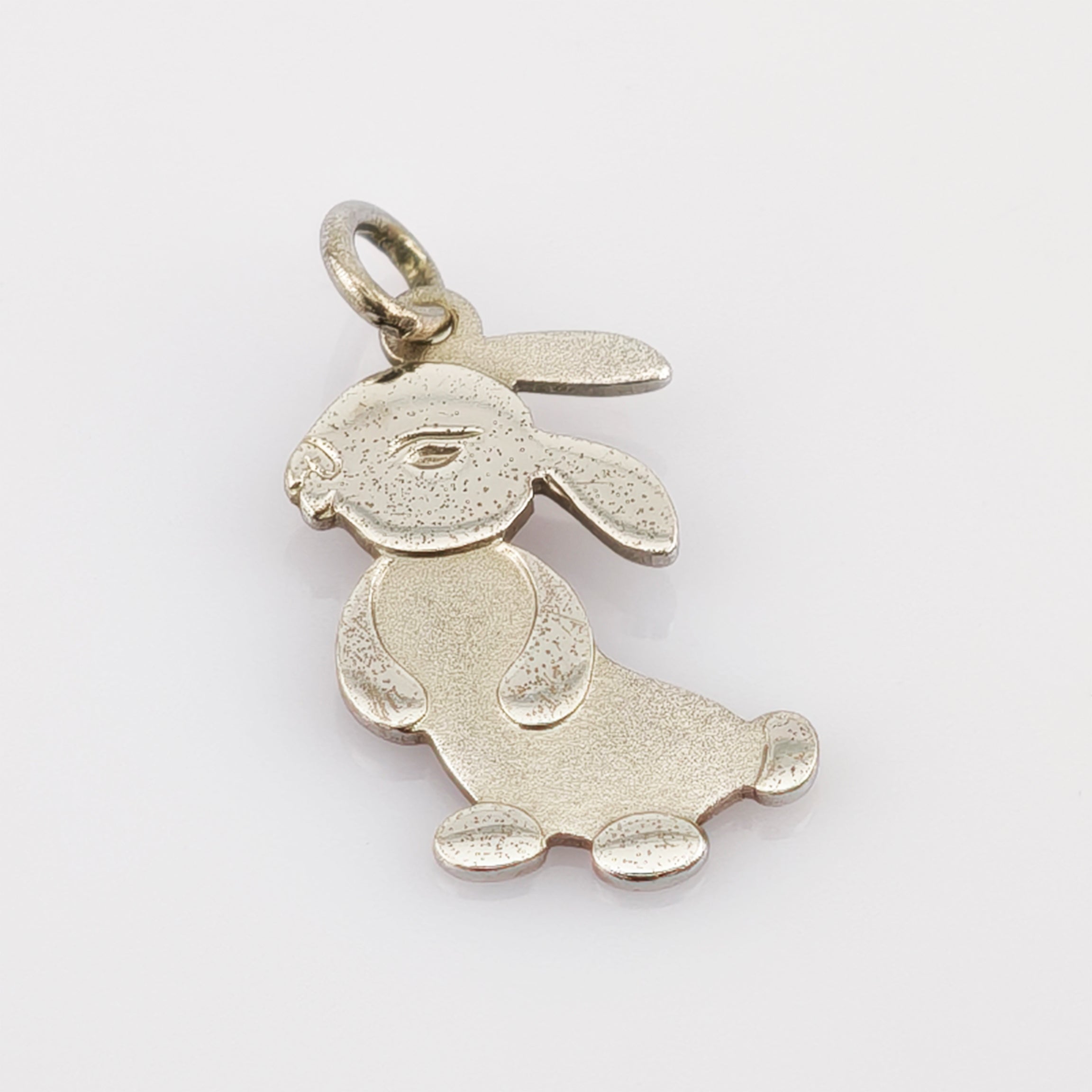 Silberfarbener Anhänger in Kaninchenform mit detaillierten Gesichtszügen und einem Ring zum Befestigen an Schmuck.