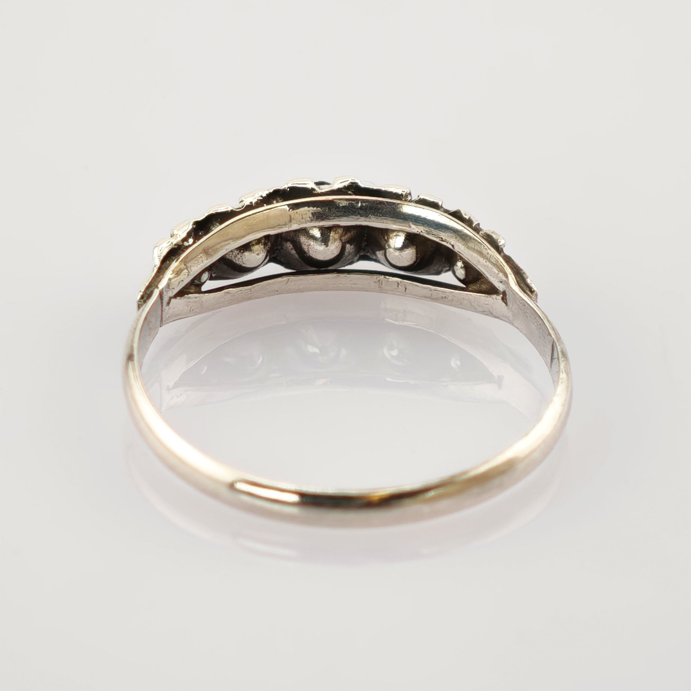 Silberfarbener Ring mit sichtbarer Innenseite und Fassung auf spiegelnder weißer Oberfläche