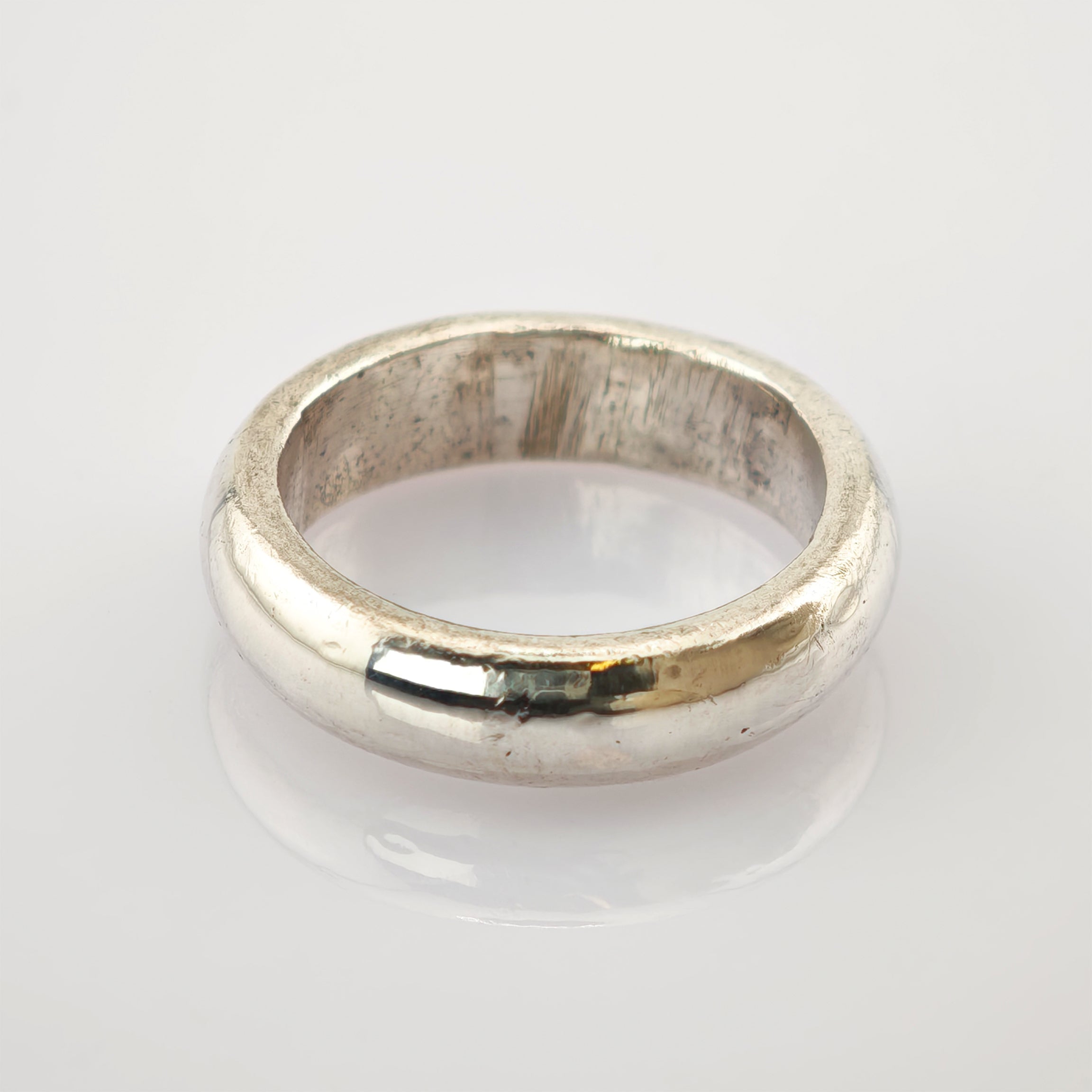 Silberner Bandring mit glänzender, leicht abgenutzter Oberfläche auf weißem Hintergrund