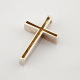 Silberner Kreuzanhänger mit hohlem Design auf glänzend weißem Untergrund.