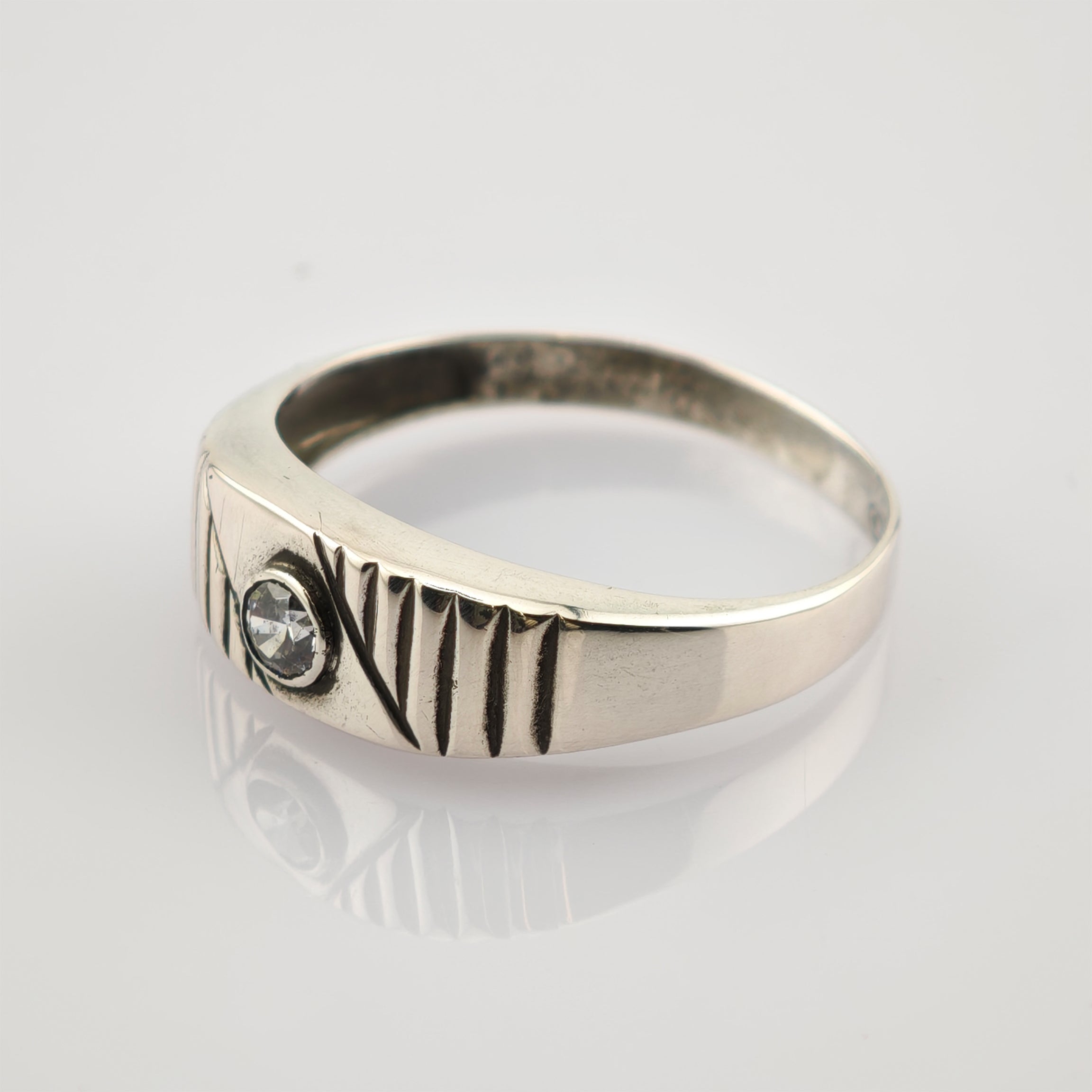 Silberner Ring mit eingraviertem AN VIII Schriftzug und klarem Stein auf reflektierender Oberfläche