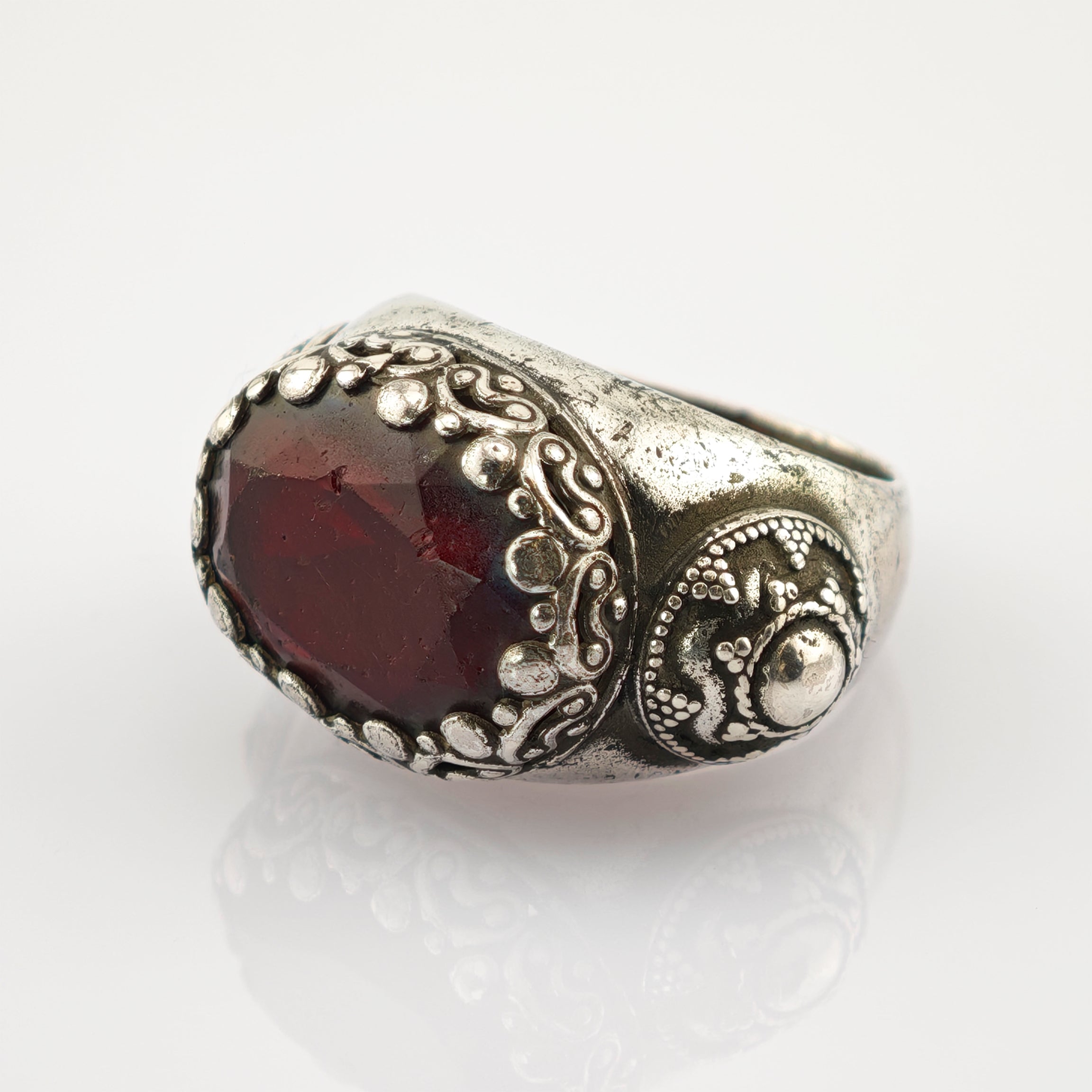 Silberner Ring mit facettiertem dunkelrotem Edelstein und viktorianischem Muster