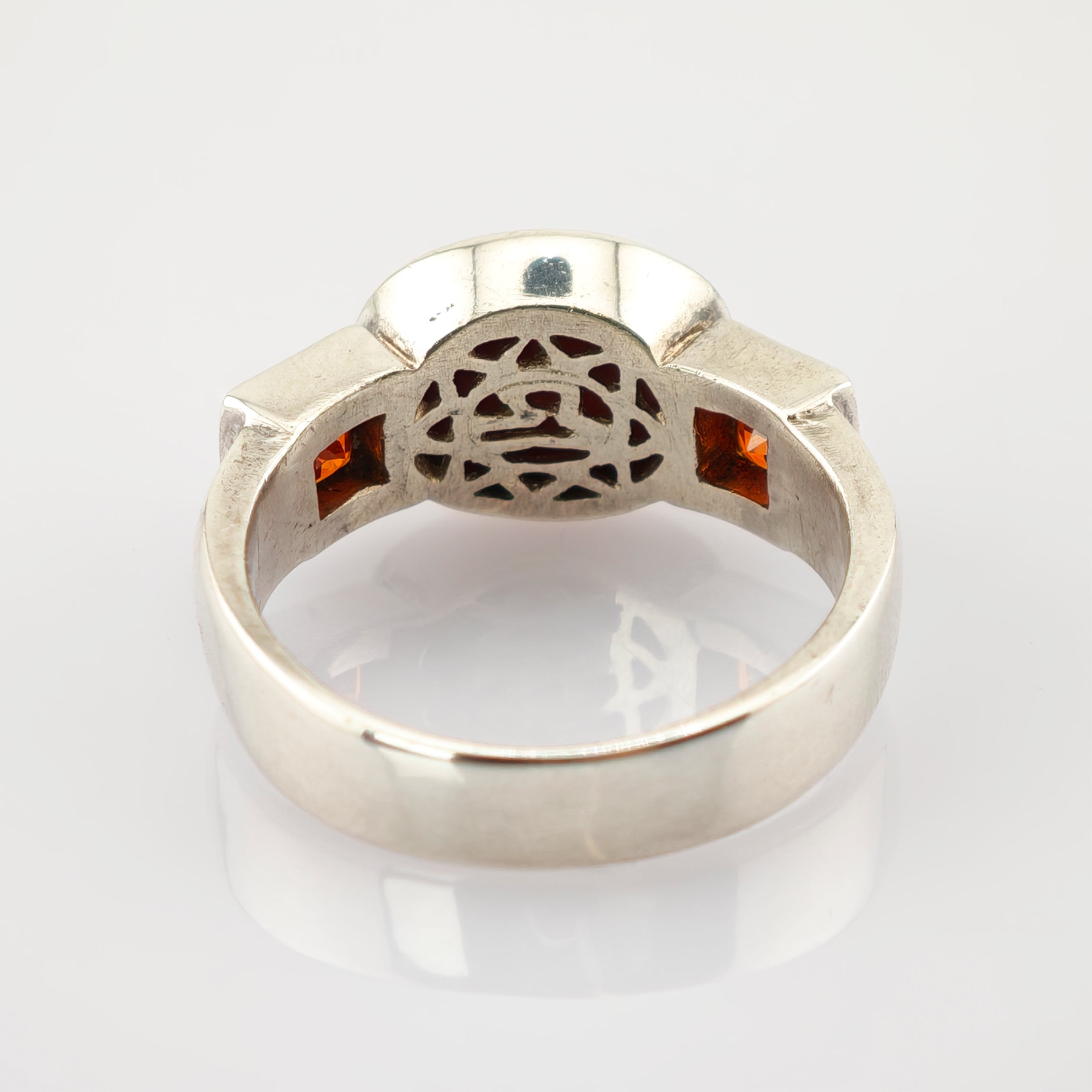 Silberner Ring mit filigranen Mustern und zwei kleinen quadratischen orangen Edelsteinen an den Seiten