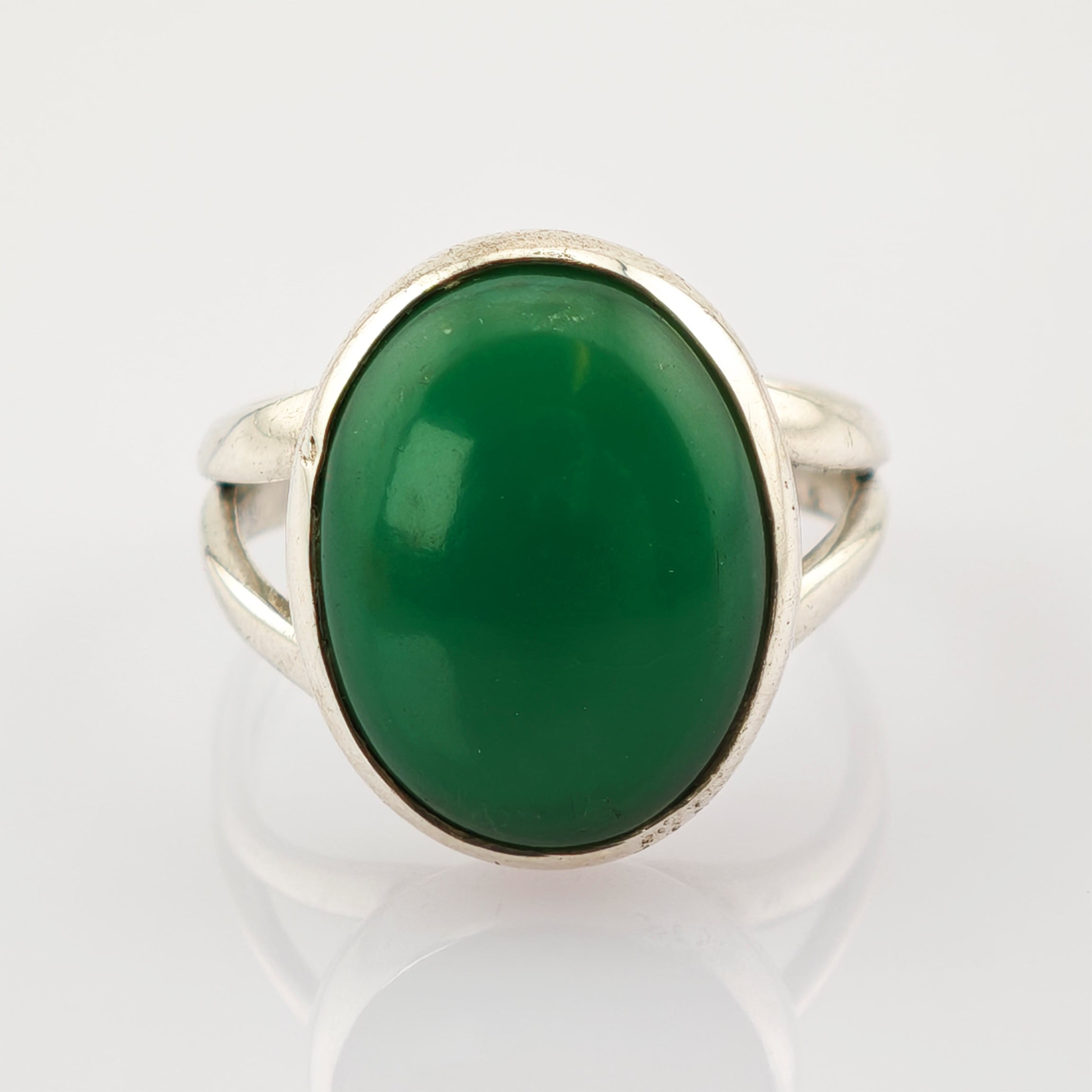 Eleganter silberner Ring mit großem ovalem grünem Edelstein auf weißem Hintergrund.