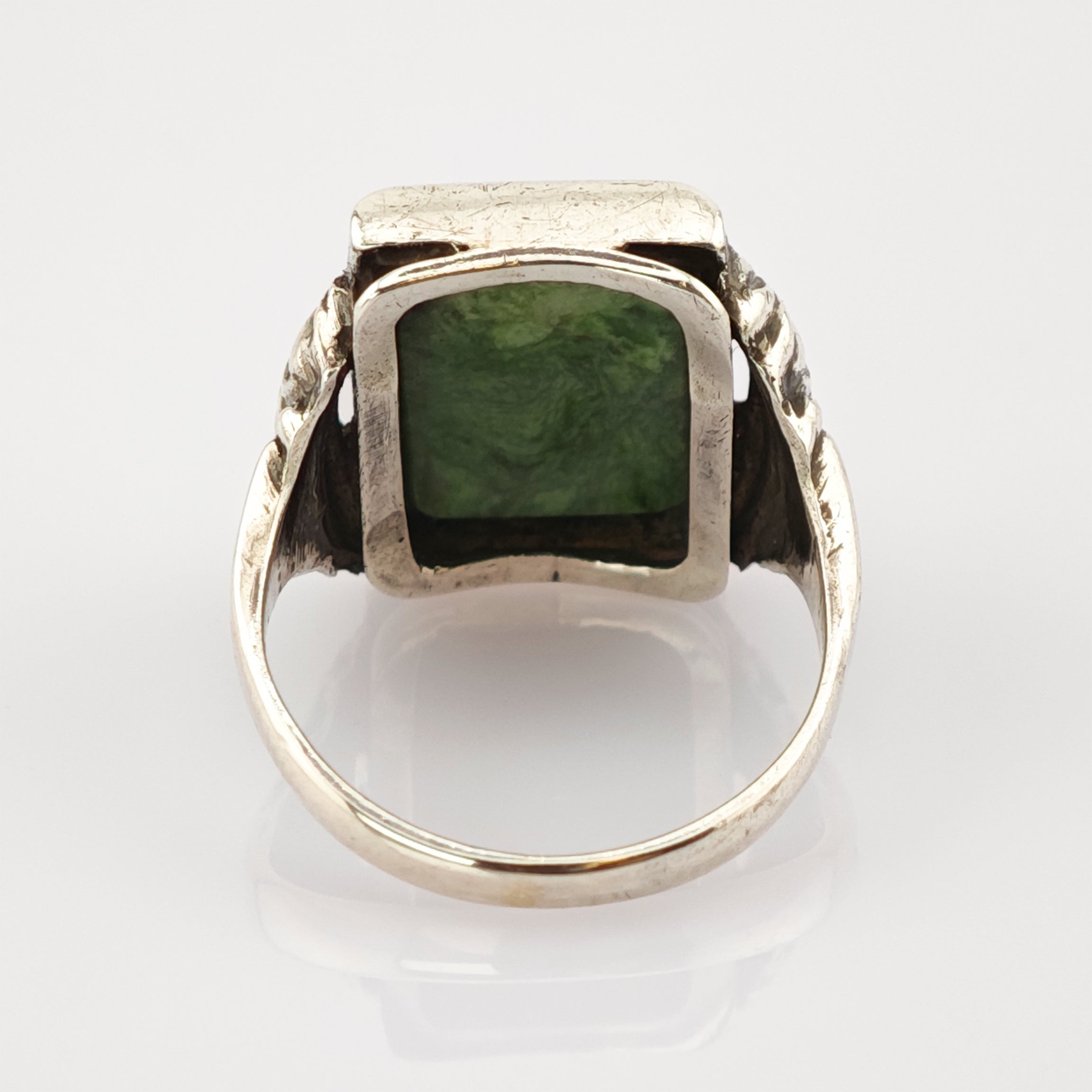 Silberner Ring mit quadratischem grünem Edelstein und texturierten Details am Ringband.