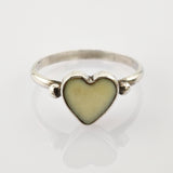 Silberner Ring mit herzförmigem gelbem Zentrum und silbernen Perlendetails auf weißem Hintergrund