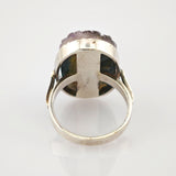 Silberner Ring mit abgerundetem Band und unregelmäßigem lila Edelstein im Setting