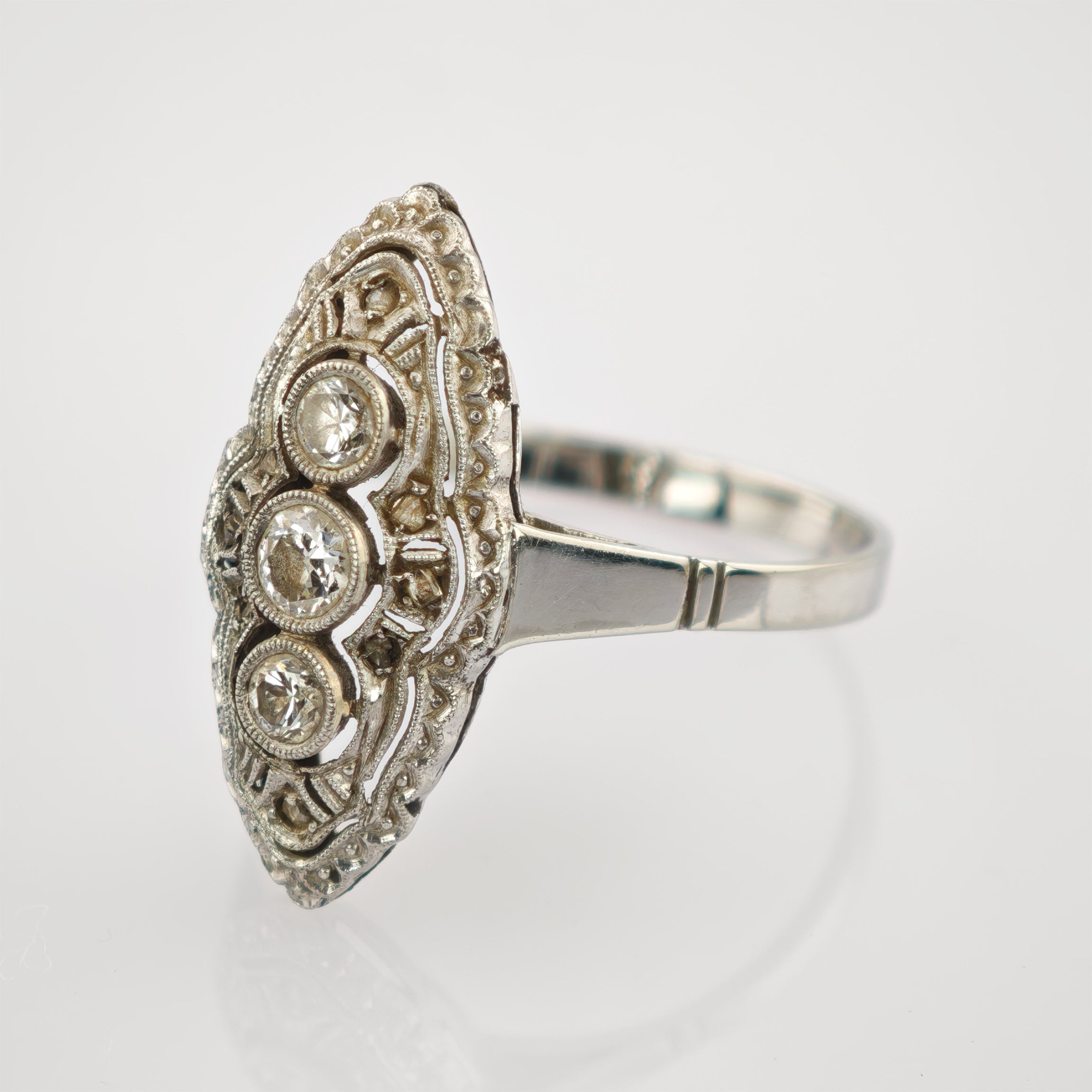 Silberner Ring mit ovaler, filigraner Oberfläche und drei waagerecht angeordneten klaren Steinen.